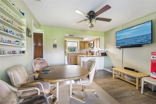 dining room featuring a textured ceiling, ceiling fan, dark wood-type flooring, and sink