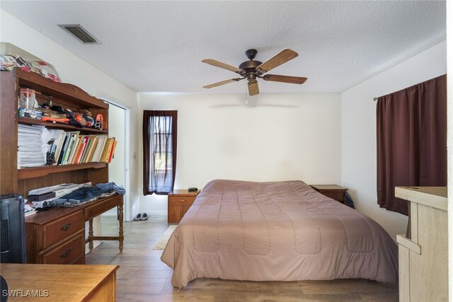 bedroom with a textured ceiling, light hardwood / wood-style floors, and ceiling fan