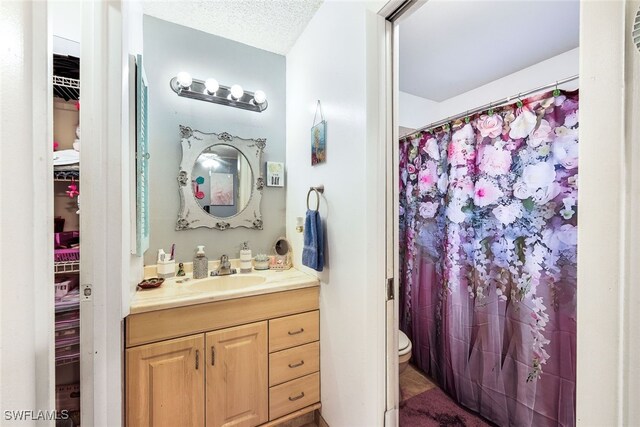 bathroom featuring a textured ceiling, vanity, toilet, and a shower with shower curtain