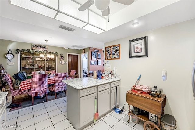 kitchen featuring kitchen peninsula, ceiling fan with notable chandelier, light tile patterned floors, and decorative light fixtures