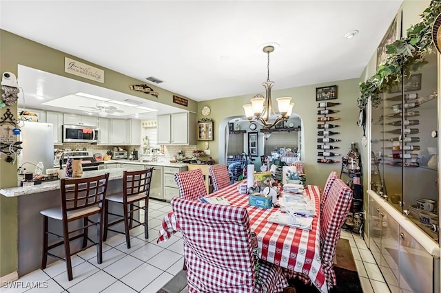 tiled dining room with ceiling fan with notable chandelier