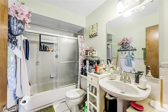 full bathroom featuring toilet, sink, tile patterned flooring, and combined bath / shower with glass door