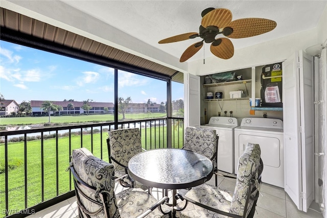 sunroom / solarium featuring washing machine and dryer, a ceiling fan, and a water view