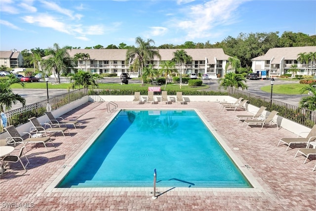 community pool featuring a residential view, fence, and a patio