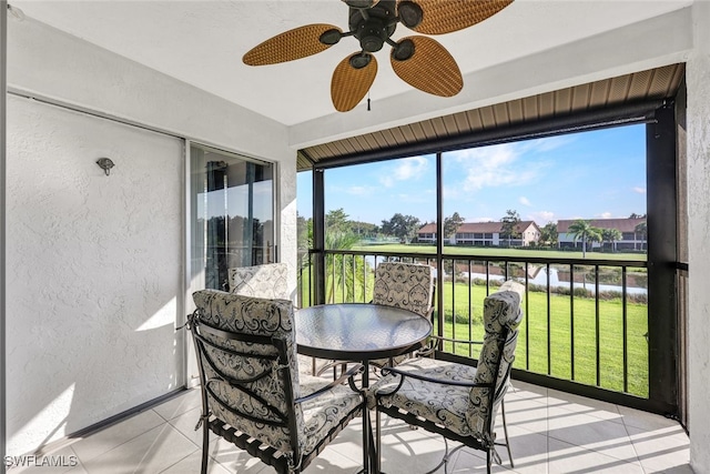 sunroom with a water view and ceiling fan