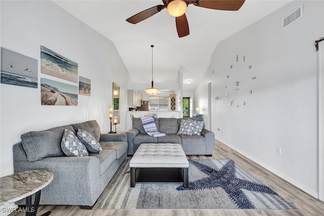 living room featuring vaulted ceiling, baseboards, visible vents, wood finished floors, and ceiling fan