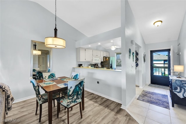 dining space featuring high vaulted ceiling, light wood finished floors, baseboards, and ceiling fan