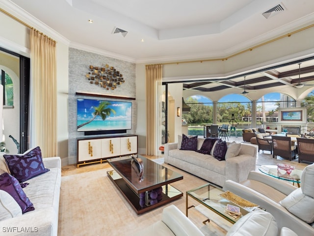 living room with crown molding, a tray ceiling, and light wood-type flooring