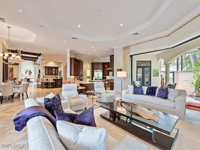 living room featuring crown molding, a notable chandelier, and a raised ceiling