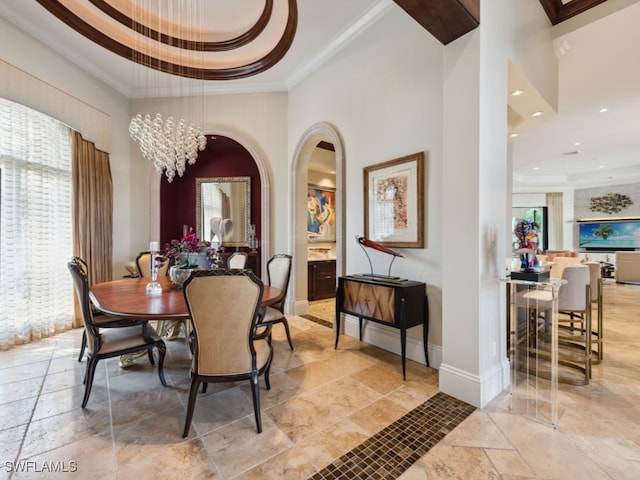 dining area with ornamental molding, a chandelier, a tray ceiling, and a high ceiling