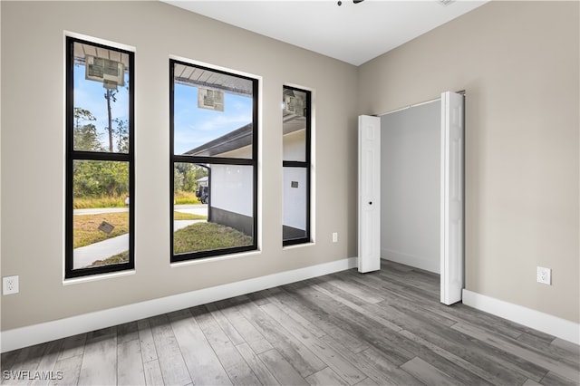 empty room with hardwood / wood-style flooring and plenty of natural light