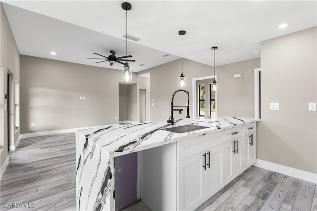 kitchen featuring white cabinets, sink, light stone countertops, and light hardwood / wood-style floors