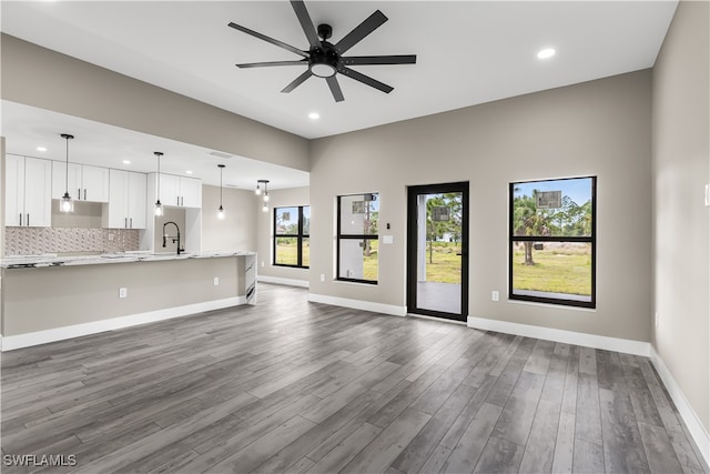 unfurnished living room with ceiling fan, dark hardwood / wood-style floors, and sink