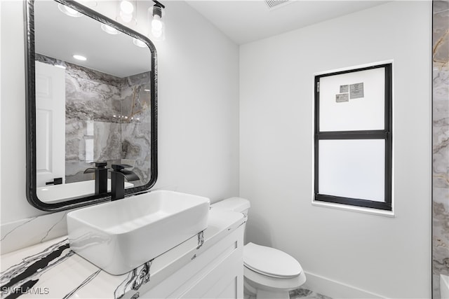 bathroom with tiled shower, vanity, and toilet