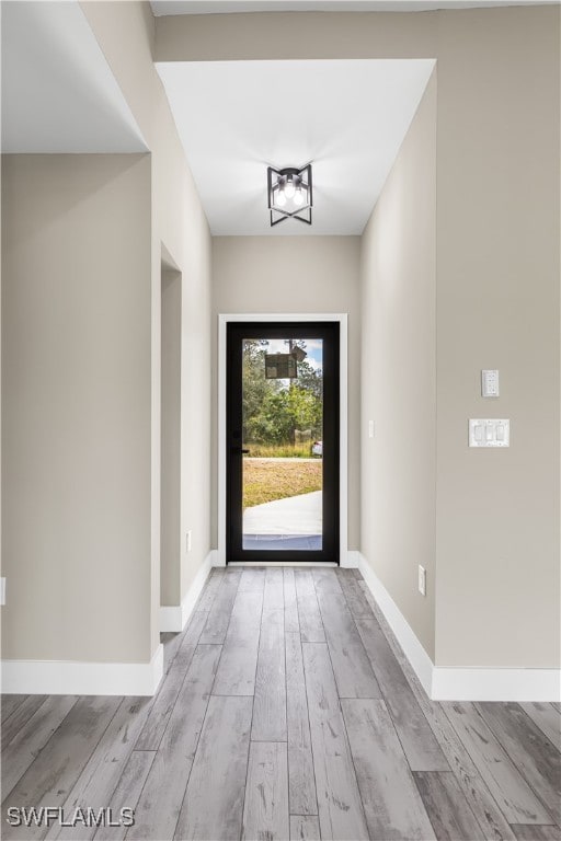 doorway to outside featuring light hardwood / wood-style floors and a chandelier