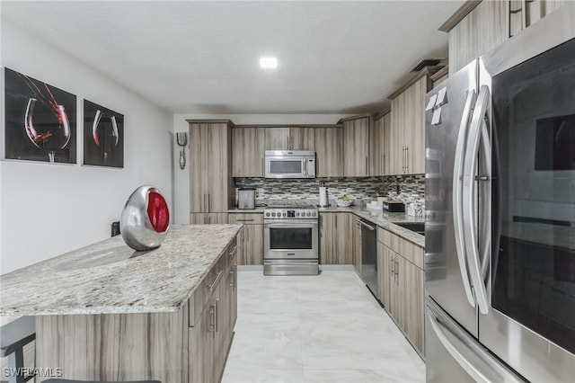 kitchen with stainless steel appliances, backsplash, light stone counters, and a kitchen island