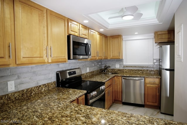 kitchen with appliances with stainless steel finishes, a raised ceiling, and dark stone countertops