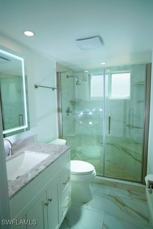 bathroom featuring vanity, toilet, and a shower with shower door