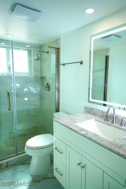 bathroom with vanity, toilet, and a shower with shower door