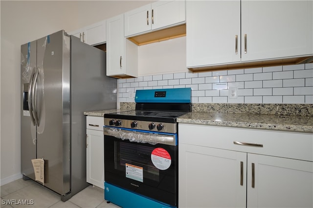 kitchen with stainless steel appliances, light stone countertops, light tile patterned floors, white cabinets, and decorative backsplash