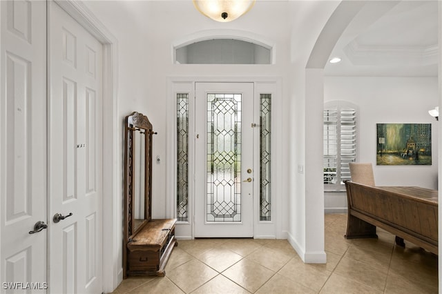 entrance foyer featuring crown molding, light tile patterned flooring, and a tray ceiling