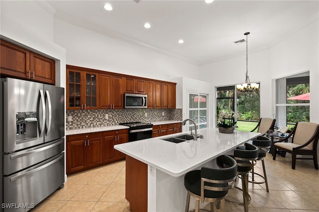 kitchen with sink, an island with sink, stainless steel appliances, crown molding, and a notable chandelier