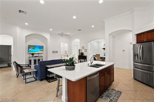 kitchen with crown molding, sink, a kitchen island with sink, and stainless steel appliances