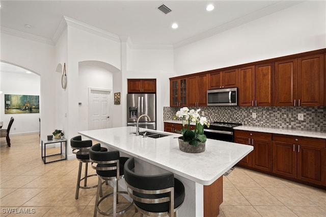 kitchen with appliances with stainless steel finishes, light tile patterned flooring, and a kitchen island with sink