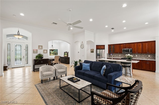 tiled living room featuring crown molding and ceiling fan