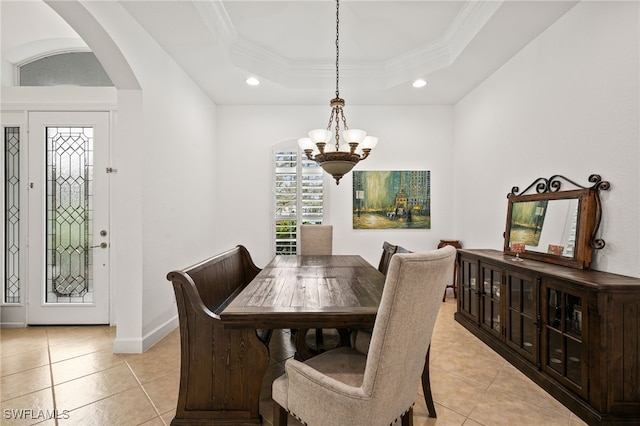 tiled dining room with crown molding, a raised ceiling, and an inviting chandelier