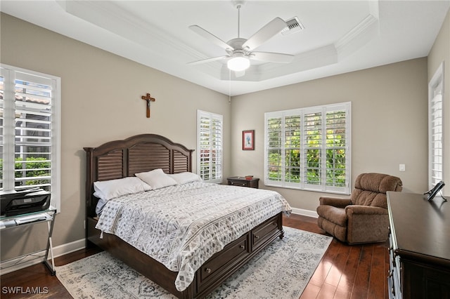 bedroom with dark wood-type flooring, ceiling fan, a raised ceiling, and multiple windows