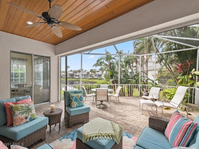 view of patio / terrace featuring outdoor lounge area, a water view, glass enclosure, and ceiling fan