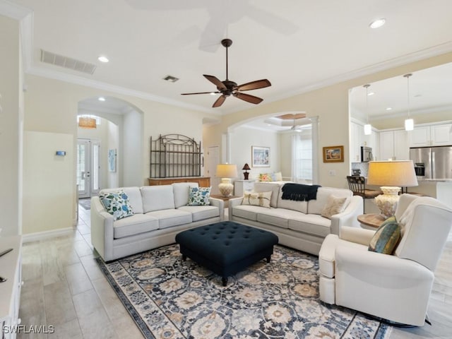 living room with crown molding, french doors, ceiling fan, and light wood-type flooring