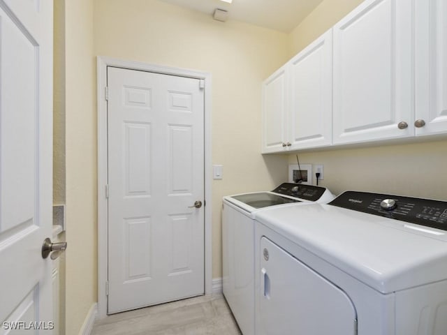 washroom featuring cabinets, independent washer and dryer, and light hardwood / wood-style flooring