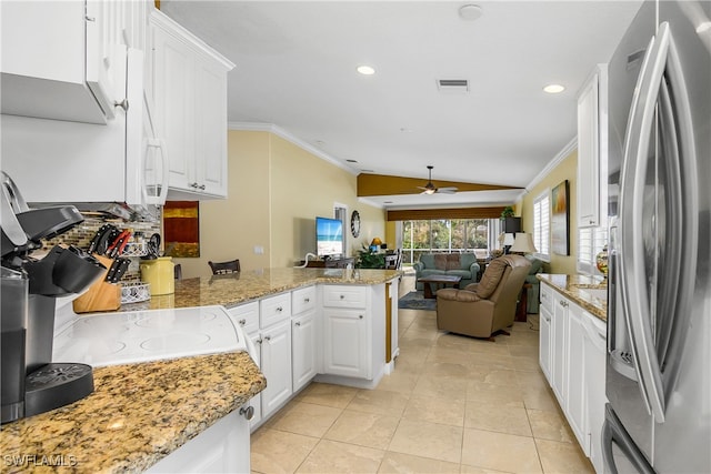 kitchen with lofted ceiling, white cabinets, stainless steel refrigerator with ice dispenser, ceiling fan, and kitchen peninsula