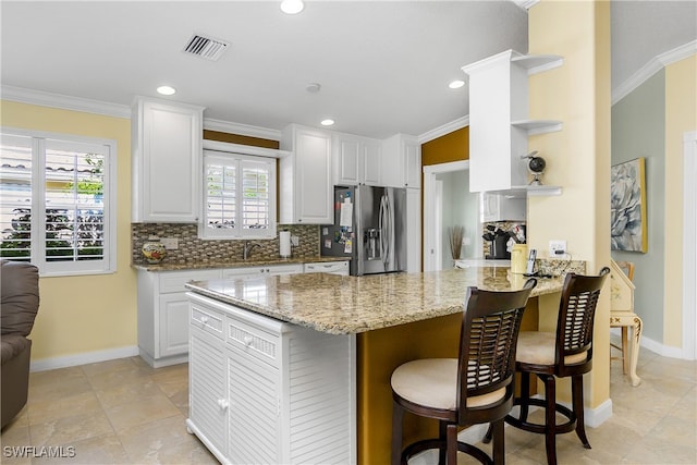 kitchen featuring a peninsula, visible vents, ornamental molding, open shelves, and stainless steel fridge