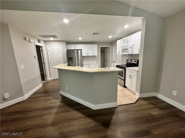 kitchen with white cabinetry, appliances with stainless steel finishes, hardwood / wood-style flooring, and a center island