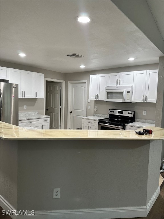 kitchen featuring light stone counters, white cabinets, stainless steel appliances, and dark wood-type flooring