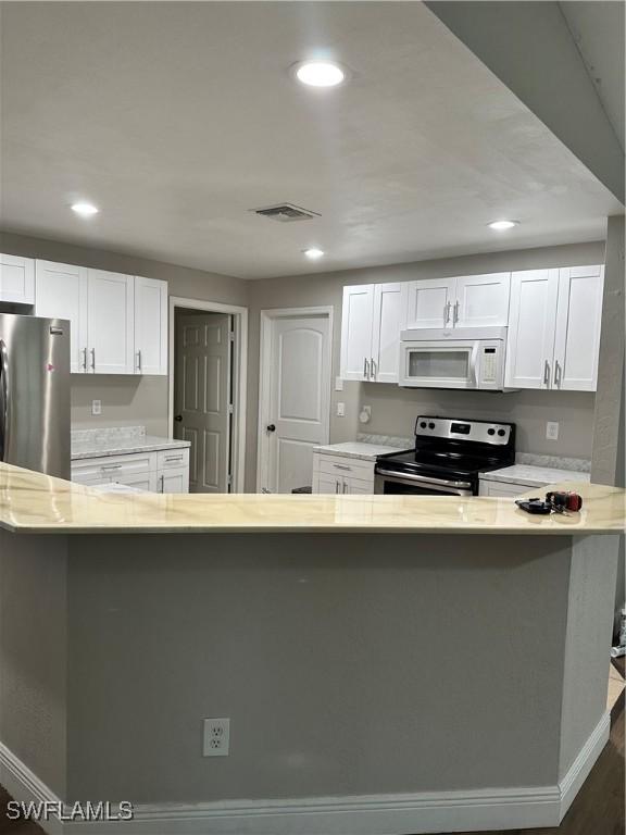 2611 4th St SW, Lehigh Acres, FL 33976 - kitchen featuring stainless steel appliances, white cabinets, baseboards, and recessed lighting