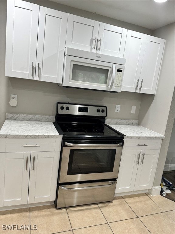 kitchen with white cabinets, light stone counters, stainless steel electric stove, and light tile patterned flooring