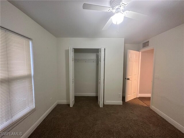 2611 4th St SW, Lehigh Acres, FL 33976 - unfurnished bedroom featuring dark carpet, a closet, baseboards, and a ceiling fan