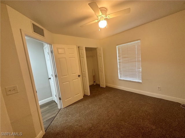 unfurnished bedroom with ceiling fan and dark carpet