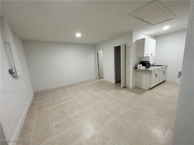2611 4th St SW, Lehigh Acres, FL 33976 - unfurnished living room with recessed lighting, light tile patterned floors, a sink, a textured wall, and baseboards