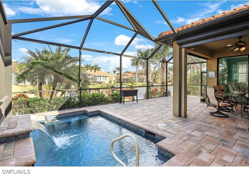 view of pool with a patio, glass enclosure, ceiling fan, and pool water feature