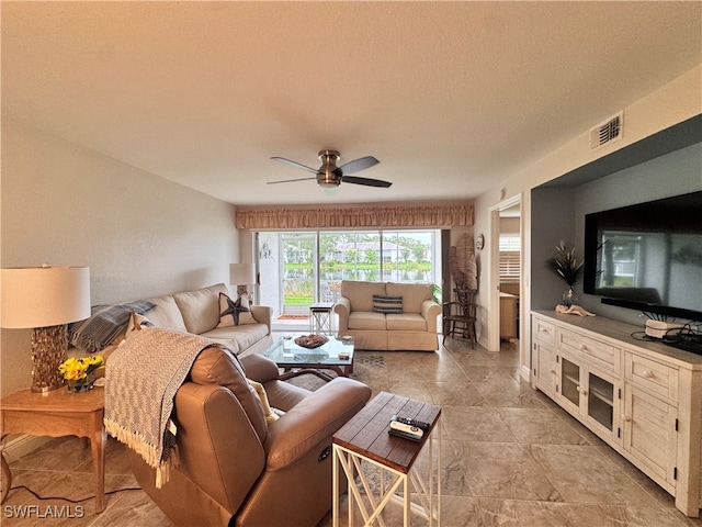 living room featuring ceiling fan and a textured ceiling