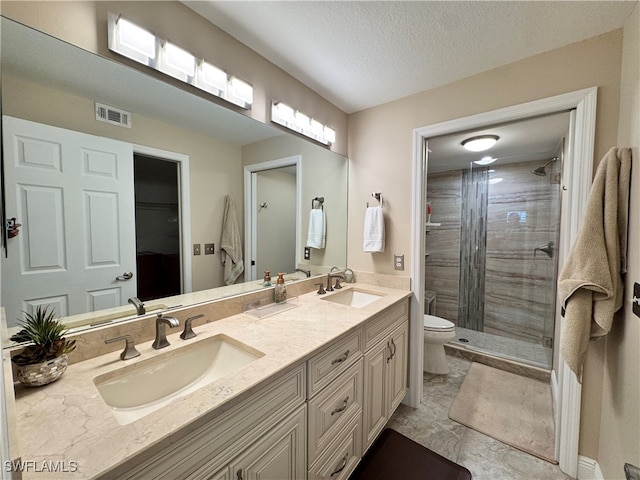 bathroom with a textured ceiling, an enclosed shower, vanity, and toilet