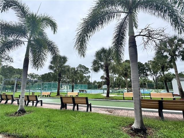 view of property's community featuring a yard and tennis court