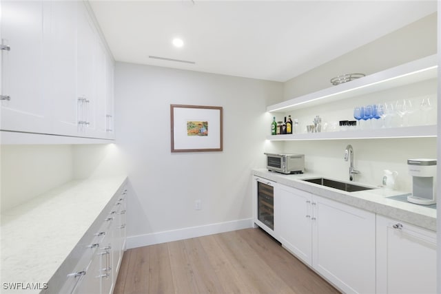 bar with wine cooler, sink, light hardwood / wood-style flooring, and white cabinetry