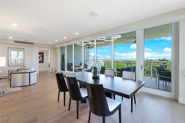 dining space with light hardwood / wood-style flooring, an inviting chandelier, and plenty of natural light