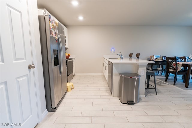 kitchen featuring white cabinets, light tile patterned flooring, sink, stainless steel appliances, and a breakfast bar area